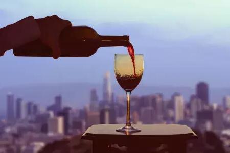 一杯红酒被poured与贝博体彩app轮廓可见的窗口.
